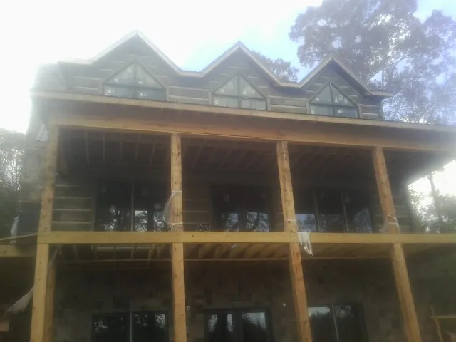 Dormers and porch framing on a large log home under construction — Roof Coating work by our crew in Farrell