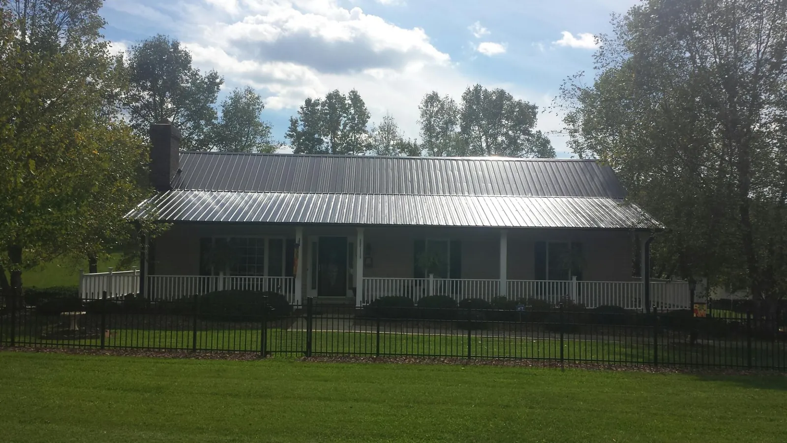 Gray metal roof on a brick ranch with a full width front porch — Gutter Guard Installation work by our crew in Farrell