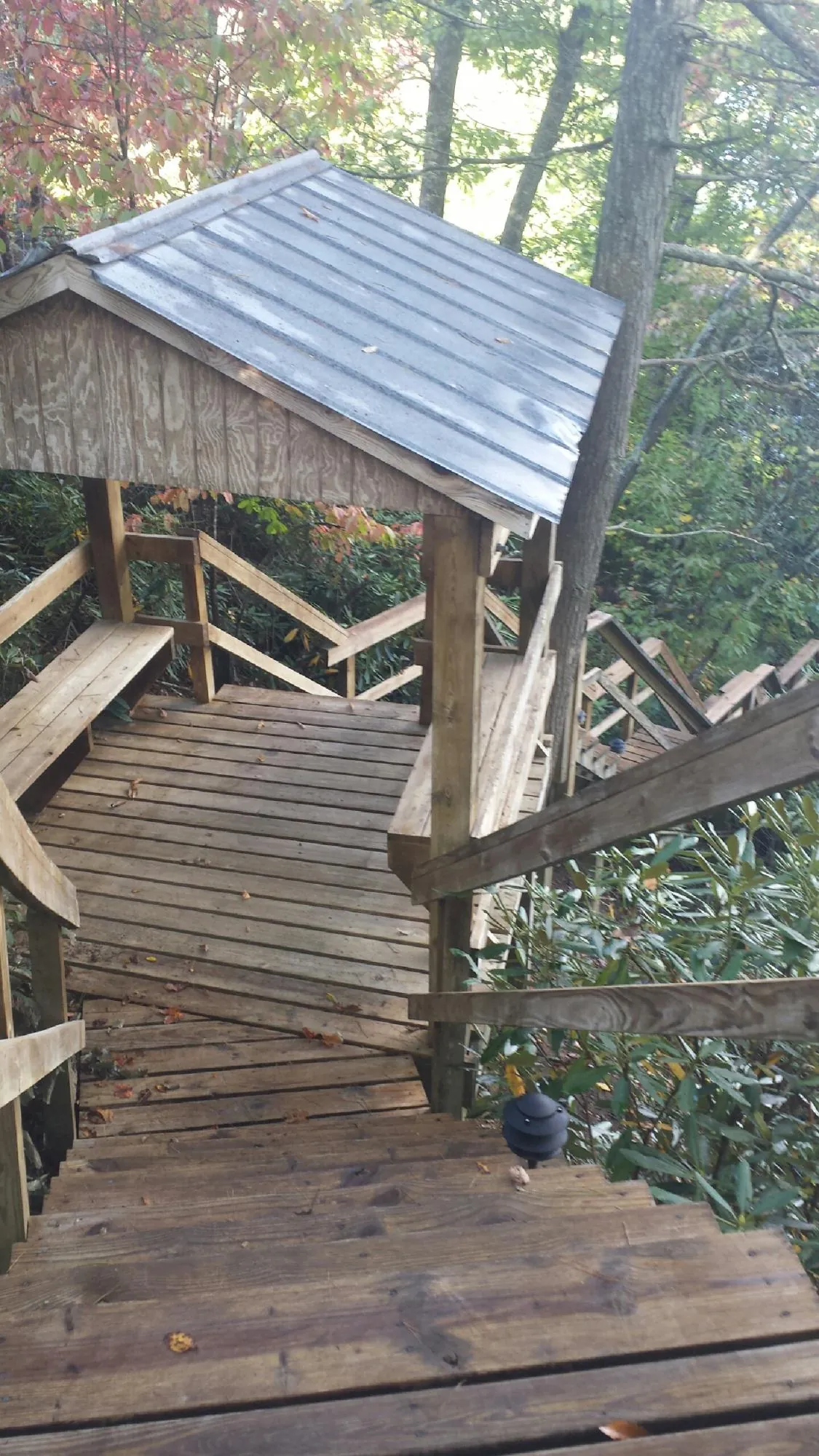 Metal roofed shelter over wooden steps on a wooded walkway — Skylight Repair & Installation work by our crew in Farrell
