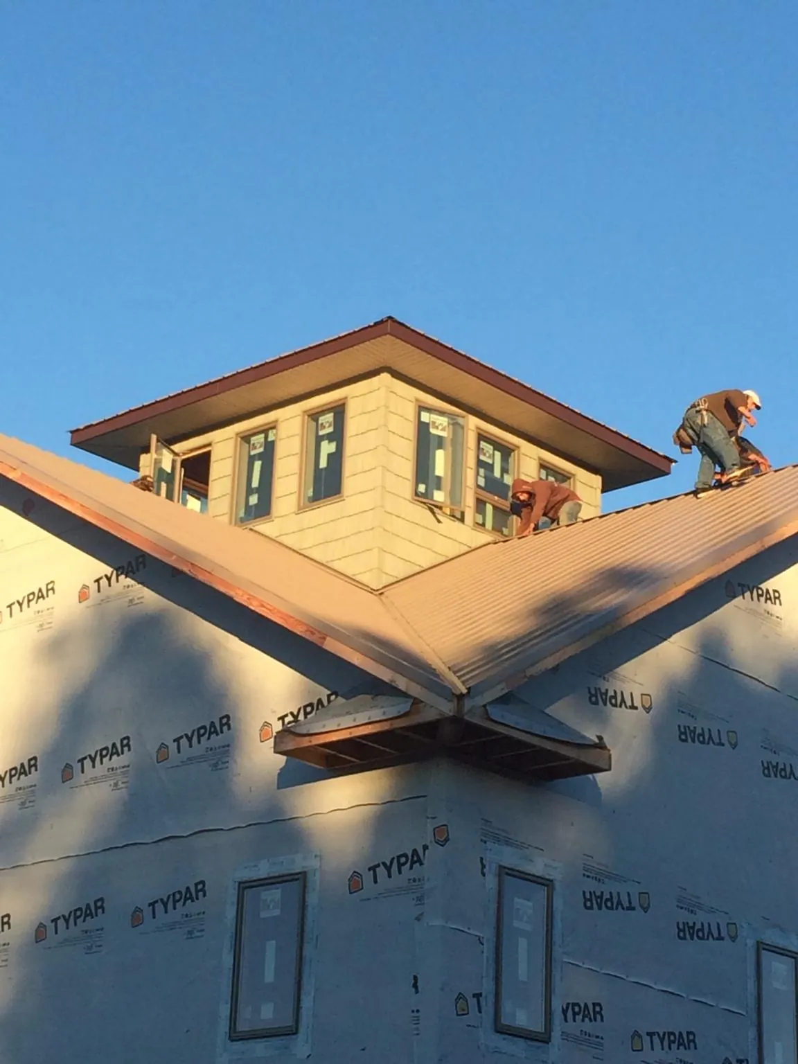 Roofers working around a rooftop cupola on a new metal roof at sunset — Roof Waterproofing in Farrell by Roofing Brothers